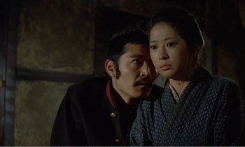 Movie still from “Empire of Passion” (1978), directed by Nagisa Ôshima – A man and a woman standing next to each other; Close Up shot, Low angle