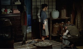 Movie still from “Empire of Passion” (1978), directed by Nagisa Ôshima – A man and a woman working in an oriental kitchen; Wide shot, High angle