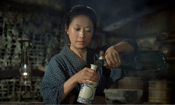 Movie still from “Empire of Passion” (1978), directed by Nagisa Ôshima – A woman in a kimono is holding something in her hand; Medium shot, High angle