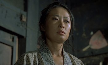 Movie still from “Empire of Passion” (1978), directed by Nagisa Ôshima – A person wearing a robe looking at the camera; Close Up shot, Low angle