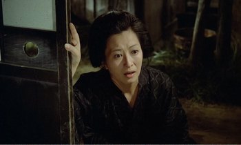 Movie still from “Empire of Passion” (1978), directed by Nagisa Ôshima – A woman in a black kimono sitting in front of a window; Medium shot, High angle