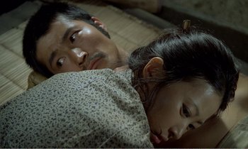 Movie still from “Empire of Passion” (1978), directed by Nagisa Ôshima – A man and a woman laying on a bed together; Close Up shot, Overhead angle