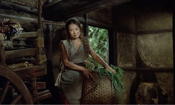 Movie still from “Empire of Passion” (1978), directed by Nagisa Ôshima – A woman holding a basket of vegetables in a room; Medium shot, Low angle