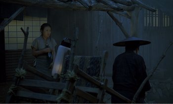 Movie still from “Empire of Passion” (1978), directed by Nagisa Ôshima – A woman standing next to a man wearing a hat; Wide shot, High angle