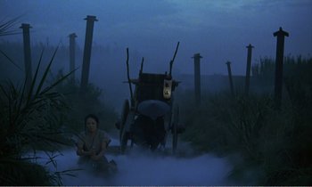 Movie still from “Empire of Passion” (1978), directed by Nagisa Ôshima – A woman sitting on the ground next to a carriage; Wide shot, Low angle