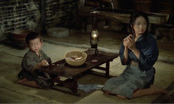 Movie still from “Empire of Passion” (1978), directed by Nagisa Ôshima – A woman and a child sitting on the floor; Wide shot, High angle