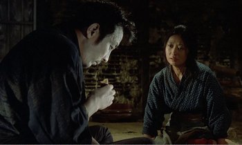 Movie still from “Empire of Passion” (1978), directed by Nagisa Ôshima – A man and a woman sitting on the ground; Medium shot, Over the shoulder angle