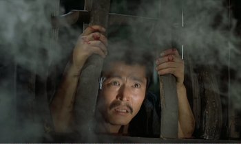 Movie still from “Empire of Passion” (1978), directed by Nagisa Ôshima – A man is looking through the bars of a prison cell; Close Up shot, Low angle