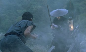 Movie still from “Empire of Passion” (1978), directed by Nagisa Ôshima – Two people fighting in the fog with one holding an umbrella; Medium shot, Over the shoulder angle