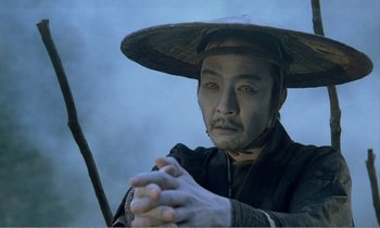 Movie still from “Empire of Passion” (1978), directed by Nagisa Ôshima – A man with a hat and a sword in his hands; Close Up shot, High angle