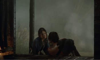 Movie still from “Empire of Passion” (1978), directed by Nagisa Ôshima – Two people sitting on the ground in the rain; Wide shot, High angle