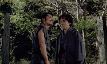 Movie still from “Empire of Passion” (1978), directed by Nagisa Ôshima – Two asian men standing next to each other in the woods; Medium shot, Low angle