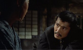 Movie still from “Empire of Passion” (1978), directed by Nagisa Ôshima – A man with a mustache is talking to another man; Close Up shot, Over the shoulder angle