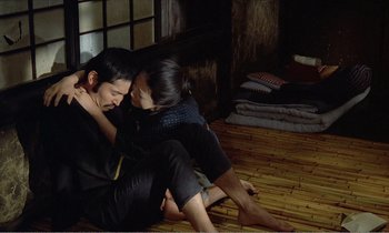 Movie still from “Empire of Passion” (1978), directed by Nagisa Ôshima – A man and a woman sitting on the ground; Medium shot, High angle