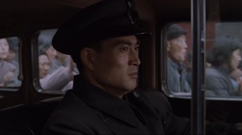 Movie still from “Empire of the Sun” (1987), directed by Steven Spielberg – A man wearing a hat sitting in a car; Close Up shot, Low angle