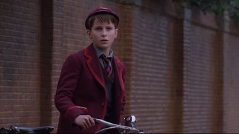 Movie still from “Empire of the Sun” (1987), directed by Steven Spielberg – A boy in a red jacket and a red hat is riding a bike; Medium shot, Low angle