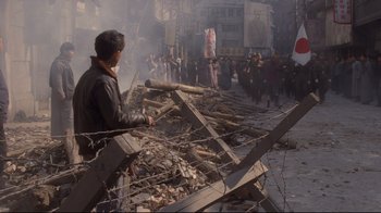 Movie still from “Empire of the Sun” (1987), directed by Steven Spielberg – A man standing next to a pile of debris; Wide shot, High angle