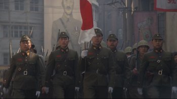 Movie still from “Empire of the Sun” (1987), directed by Steven Spielberg – A group of men in uniforms marching in a parade; Wide shot, Low angle