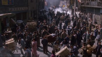 Movie still from “Empire of the Sun” (1987), directed by Steven Spielberg – A crowd of people walking down a street; Extreme Wide shot, High angle