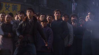 Movie still from “Empire of the Sun” (1987), directed by Steven Spielberg – A group of men standing next to each other on a street; Wide shot, Low angle