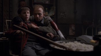 Movie still from “Empire of the Sun” (1987), directed by Steven Spielberg – Two people sitting in a room with a pan of rice; Medium shot, Low angle