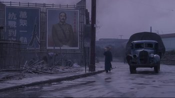 Movie still from “Empire of the Sun” (1987), directed by Steven Spielberg – A man walking down the street in front of a large portrait of stalin; Extreme Wide shot, Low angle