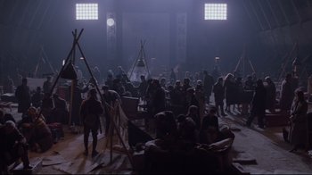 Movie still from “Empire of the Sun” (1987), directed by Steven Spielberg – A group of people sitting around in a room; Extreme Wide shot, High angle
