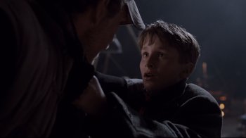 Movie still from “Empire of the Sun” (1987), directed by Steven Spielberg – A young boy looking at an older man in the dark; Close Up shot, Over the shoulder angle