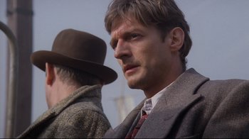 Movie still from “Empire of the Sun” (1987), directed by Steven Spielberg – A man in a suit and tie next to another man in a hat; Close Up shot, Low angle