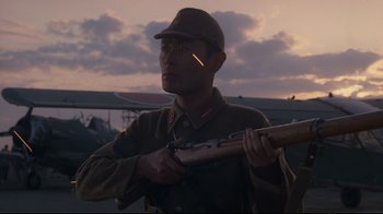 Movie still from “Empire of the Sun” (1987), directed by Steven Spielberg – A man holding a rifle in front of a sky background; Medium shot, Low angle
