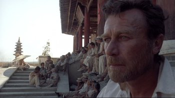 Movie still from “Empire of the Sun” (1987), directed by Steven Spielberg – A group of people sitting on a wall; Close Up shot, Low angle