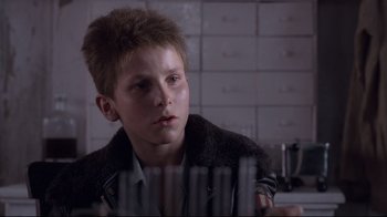 Movie still from “Empire of the Sun” (1987), directed by Steven Spielberg – A young boy is looking at a row of files; Close Up shot, Over the shoulder angle