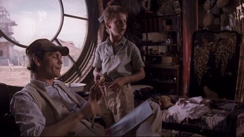 Movie still from “Empire of the Sun” (1987), directed by Steven Spielberg – Two young men are in a room with many items; Medium shot, Over the shoulder angle