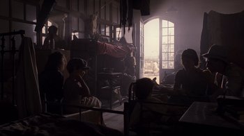 Movie still from “Empire of the Sun” (1987), directed by Steven Spielberg – A group of people sitting around in a room; Wide shot, High angle