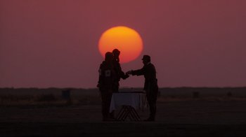 Movie still from “Empire of the Sun” (1987), directed by Steven Spielberg – Two men shake hands in front of the setting sun; Wide shot, Low angle