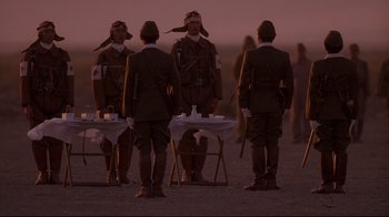 Movie still from “Empire of the Sun” (1987), directed by Steven Spielberg – A group of men standing next to each other on top of a field; Wide shot, Low angle
