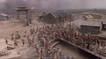 Movie still from “Empire of the Sun” (1987), directed by Steven Spielberg – An image of a crowd of people in the middle of a town; Extreme Wide shot, High angle