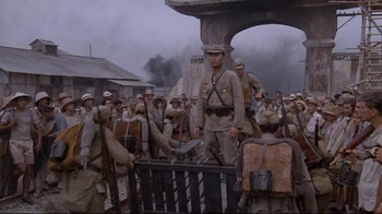 Movie still from “Empire of the Sun” (1987), directed by Steven Spielberg – A group of men standing next to each other on a street; Wide shot, High angle
