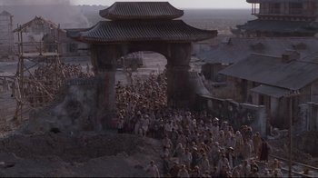 Movie still from “Empire of the Sun” (1987), directed by Steven Spielberg – A crowd of people standing in front of an archway; Extreme Wide shot, High angle