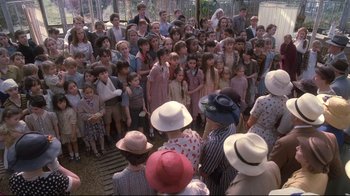 Movie still from “Empire of the Sun” (1987), directed by Steven Spielberg – A group of people standing in a crowd wearing hats; Wide shot, High angle