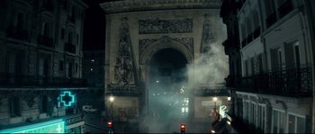 Movie still from “Empire of the Wolves” (2005), directed by Chris Nahon – A street scene with a large arch in the middle of the night; Extreme Wide shot, Over the shoulder angle