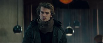 Movie still from “Empire of the Wolves” (2005), directed by Chris Nahon – A man wearing a black jacket and a brown scarf; Close Up shot, Over the shoulder angle