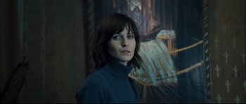 Movie still from “Empire of the Wolves” (2005), directed by Chris Nahon – A woman standing in front of a painting; Close Up shot, Low angle