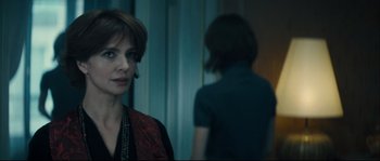 Movie still from “Empire of the Wolves” (2005), directed by Chris Nahon – A woman standing in front of a man in a room; Close Up shot, Over the shoulder angle