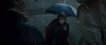 Movie still from “Empire of the Wolves” (2005), directed by Chris Nahon – A woman holding an umbrella while standing in the rain; Medium shot, High angle