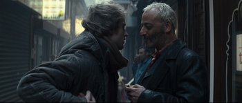 Movie still from “Empire of the Wolves” (2005), directed by Chris Nahon – Two men are talking to each other in a crowd of people; Close Up shot, Over the shoulder angle