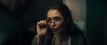 Movie still from “Empire of the Wolves” (2005), directed by Chris Nahon – A woman wearing glasses and a measuring tape around her neck; Close Up shot, Over the shoulder angle