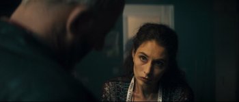 Movie still from “Empire of the Wolves” (2005), directed by Chris Nahon – A woman looking at the camera in a dark room; Close Up shot, Over the shoulder angle