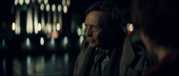 Movie still from “Empire of the Wolves” (2005), directed by Chris Nahon – An older man wearing a jacket and a scarf; Close Up shot, Over the shoulder angle