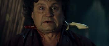Movie still from “Empire of the Wolves” (2005), directed by Chris Nahon – A man with a knife in his mouth; Close Up shot, Over the shoulder angle